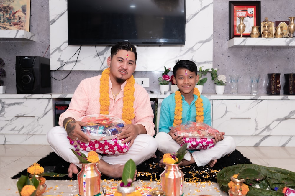 a man and woman sitting on the floor holding baskets of food