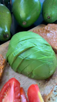 A cheerful green avocado slicer resting on a cutting board with sliced avocados ready to serve.