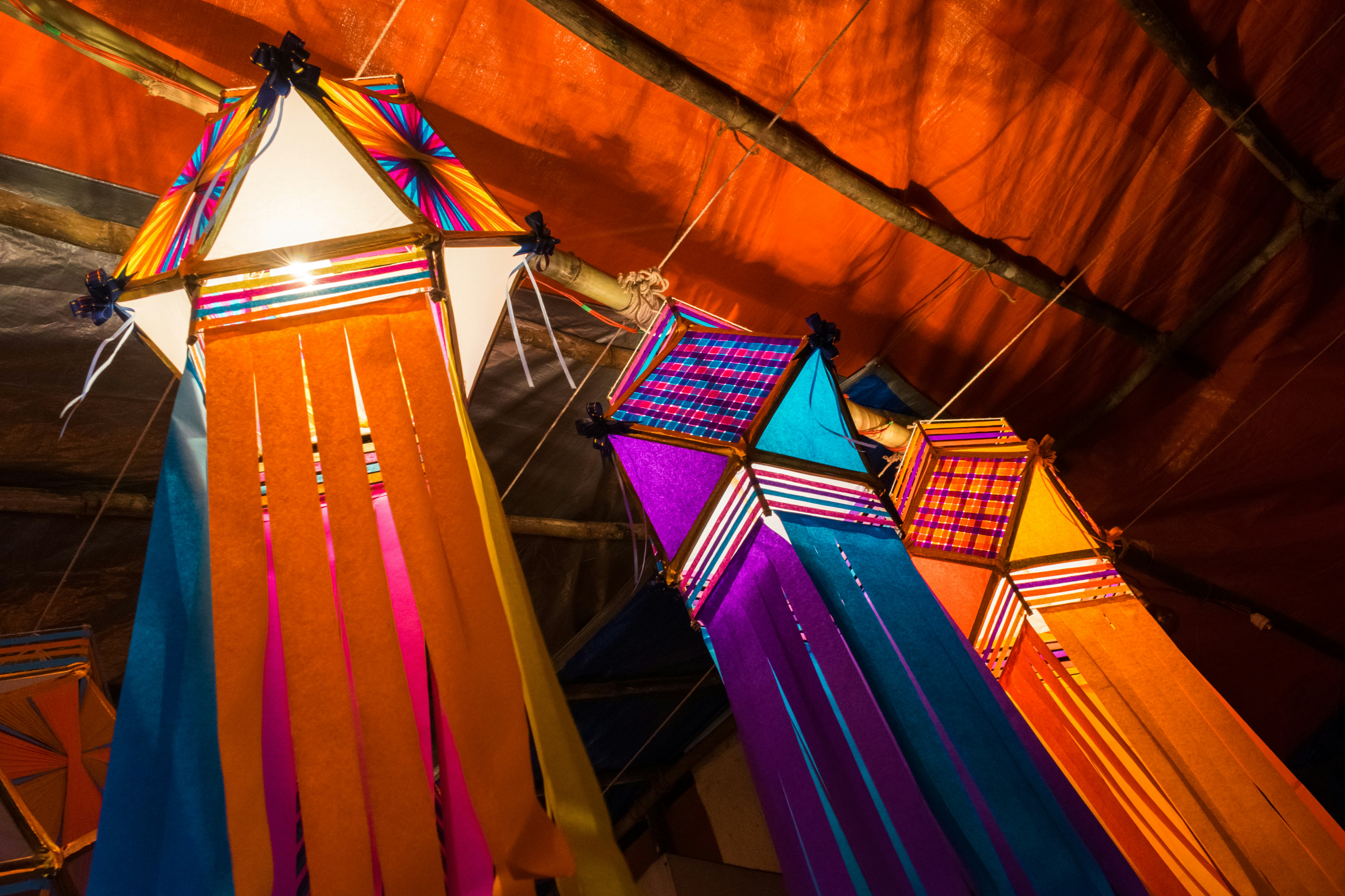 A group of colorful kites hanging from a ceiling photo Free Art Image