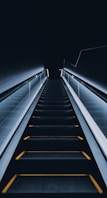 an escalator with yellow lights going down it