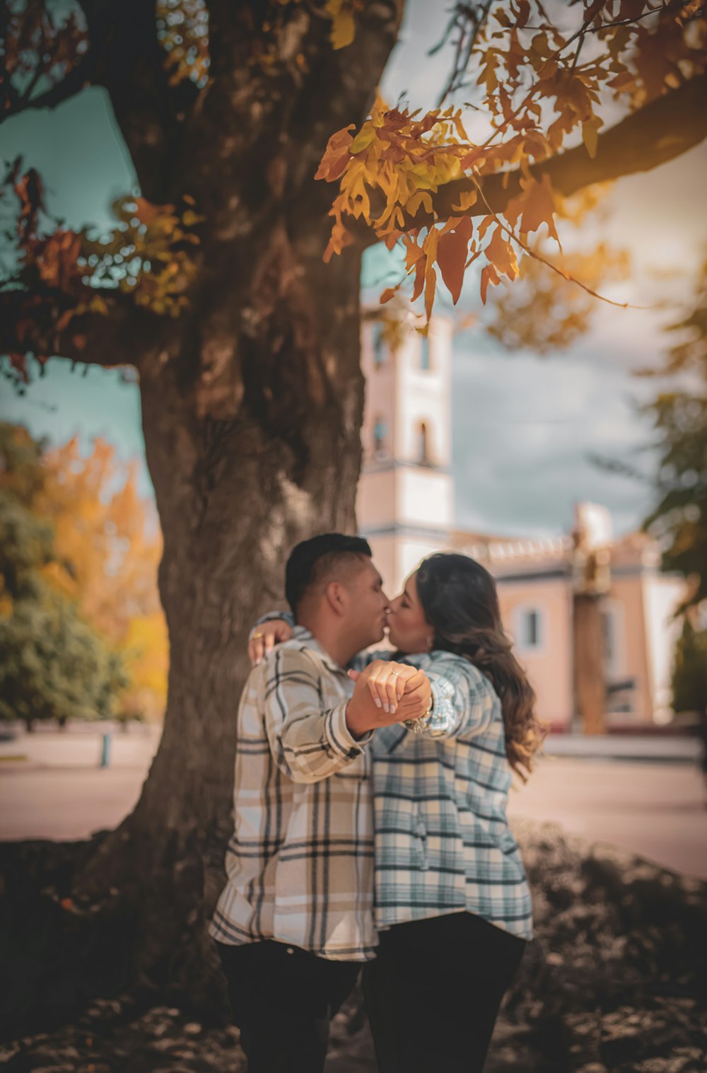 a couple kissing under a tree in front of a building