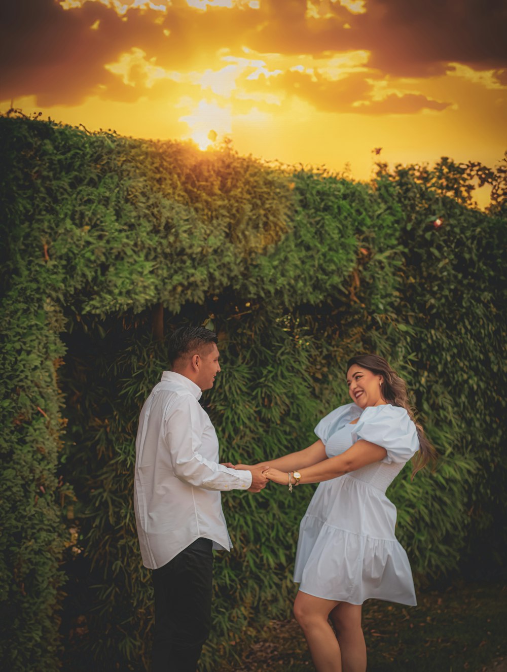 a man and a woman holding hands in front of a sunset