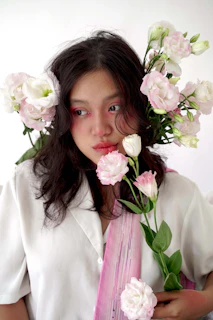 Smiling woman with glowing skin surrounded by blush pink flowers