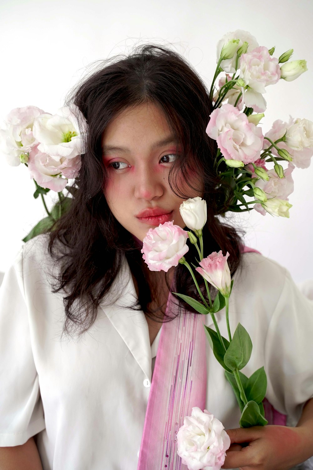 a woman with flowers in her hair holding a vase