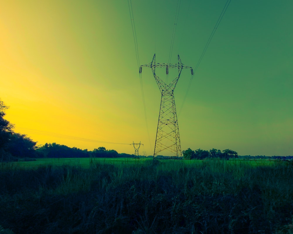 uma linha de energia de alta tensão em um campo ao pôr do sol