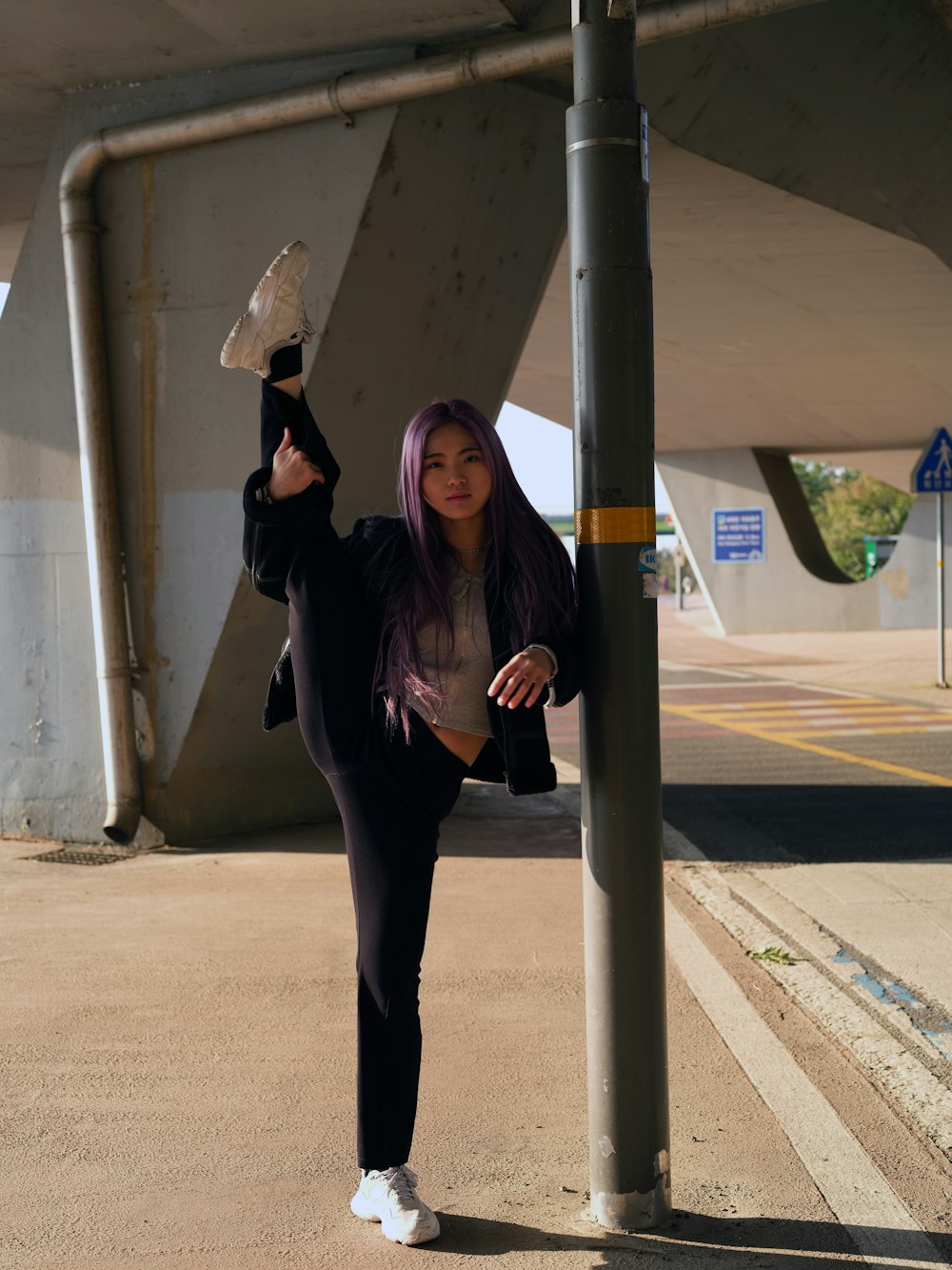 a woman with purple hair leaning against a pole