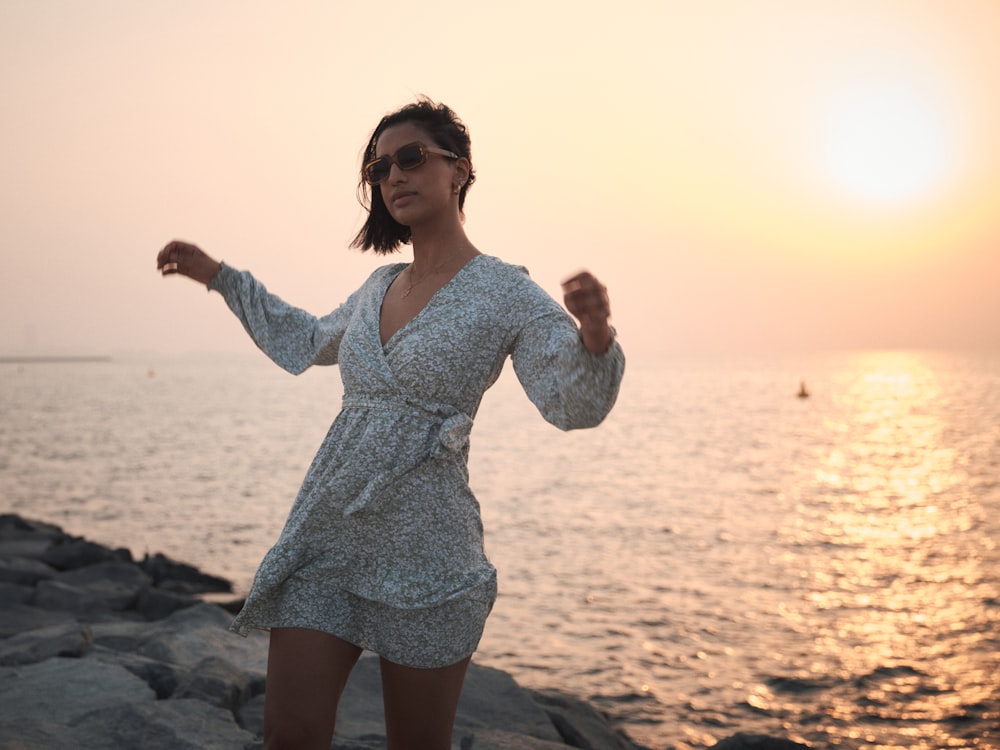 a woman standing on a rocky beach next to the ocean