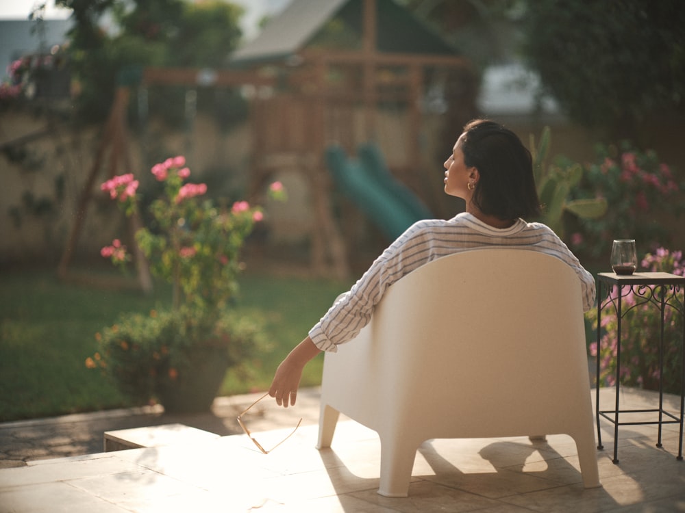a woman sitting on a chair in a backyard