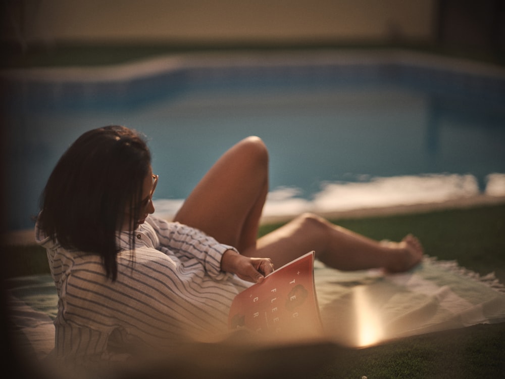 a woman laying on the ground next to a swimming pool