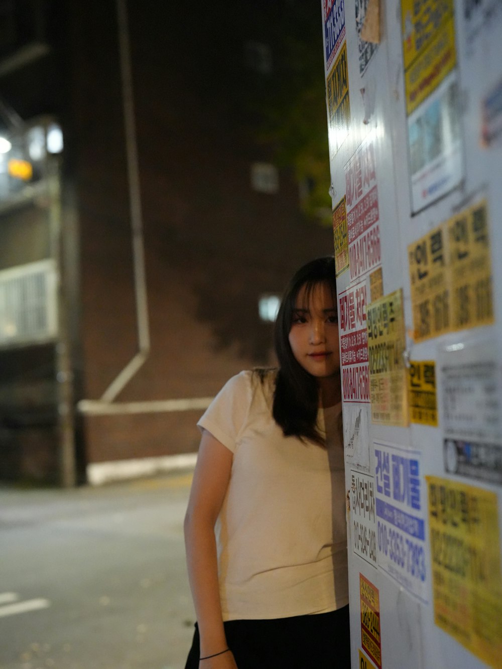 a woman leaning against a wall with a lot of stickers on it