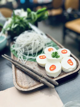 Blocks of fresh tofu artfully arranged on a wooden board with green leaves.