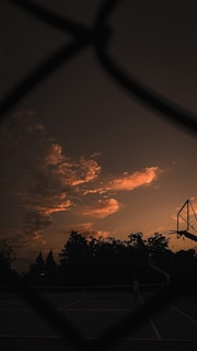 A basketball coach talking to a young athlete on the court during sunset.