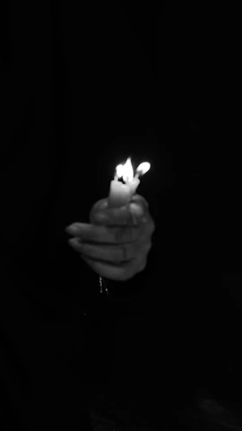 Delicate female hands holding a single tarot card with soft candlelight in the background.