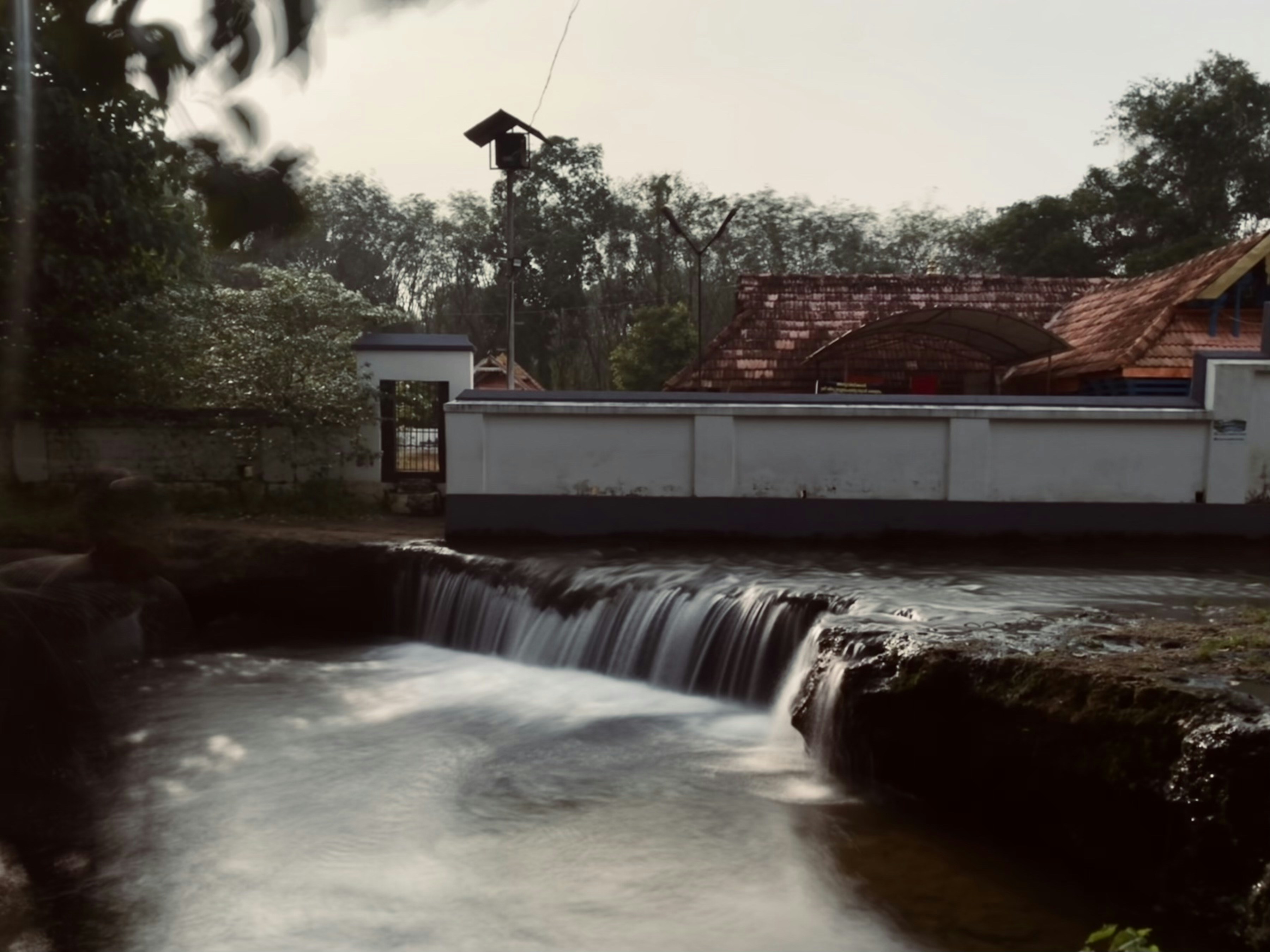 a small waterfall running into a river next to a building
