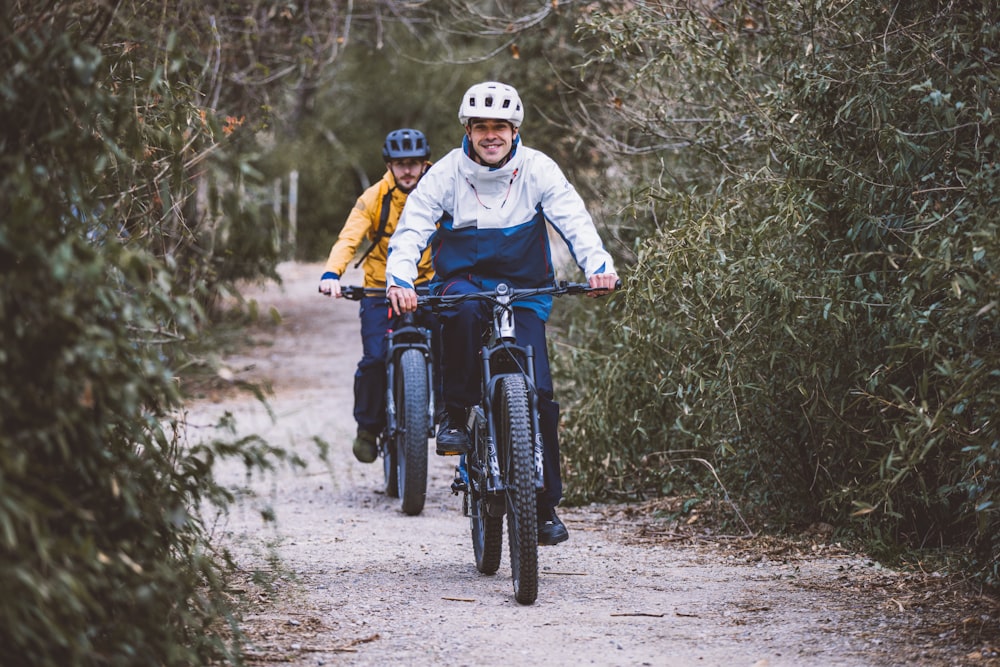 a couple of people riding bikes down a dirt road