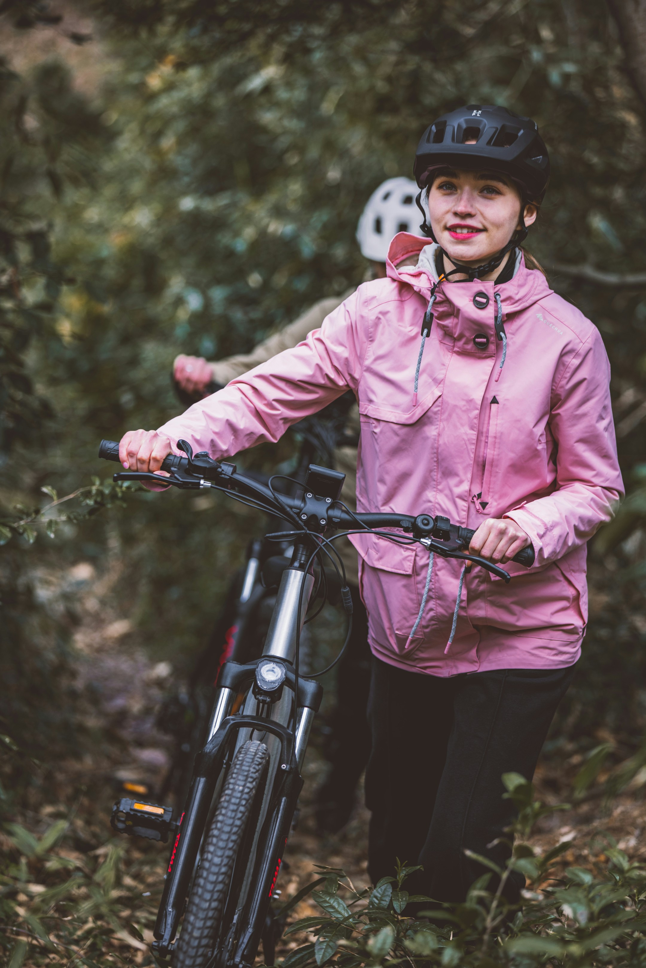a woman in a pink jacket standing next to a bike