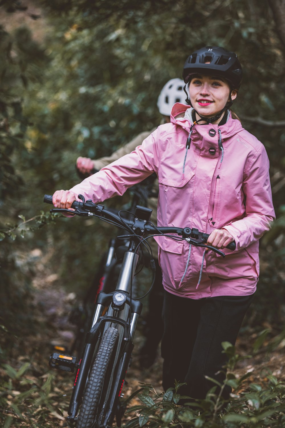a woman in a pink jacket standing next to a bike