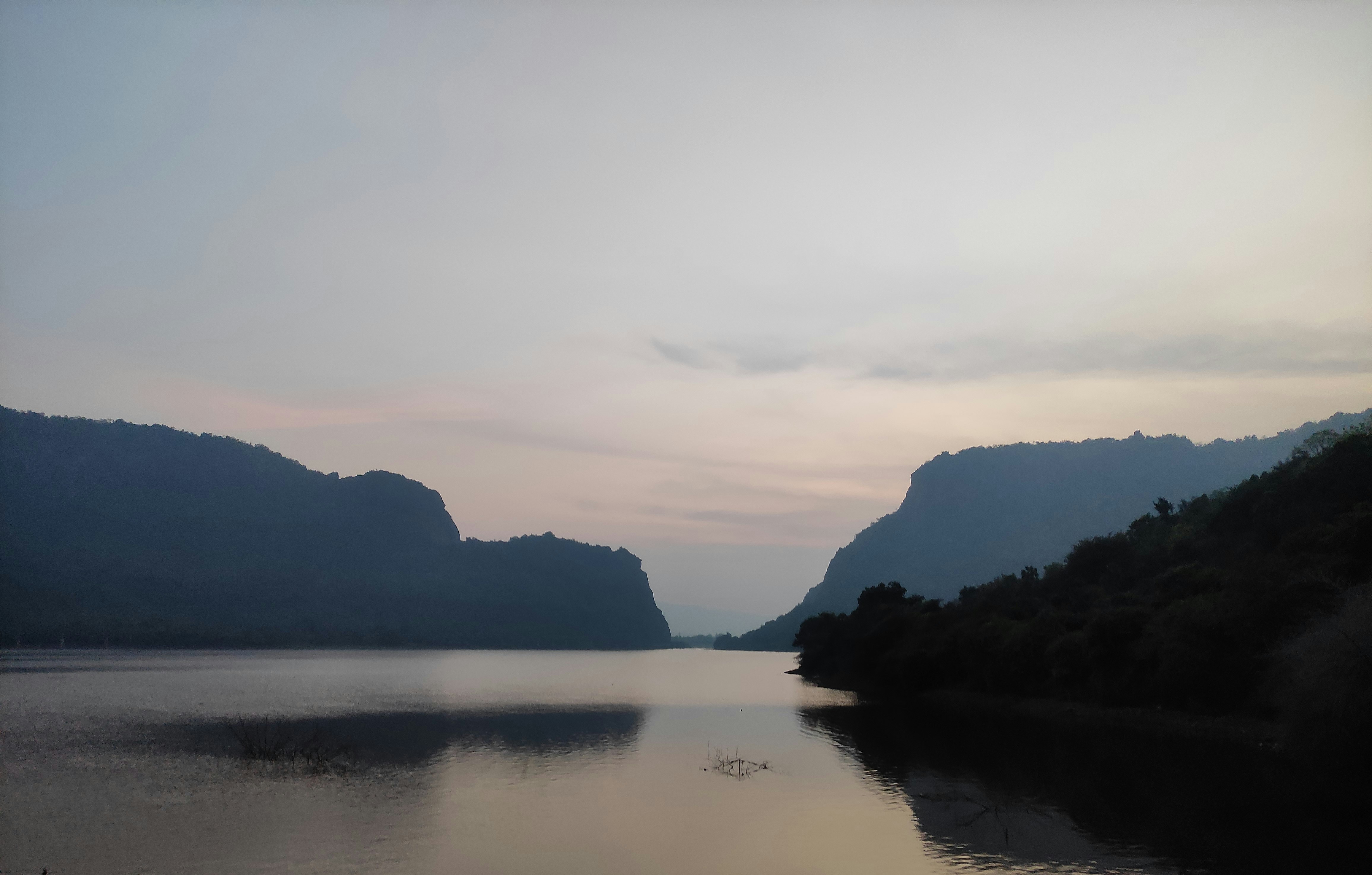 Serene mountain lake at dusk with dark reflective water