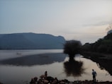 A serene landscape with a person reflecting by a lake.