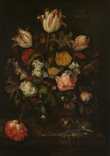 A still life arrangement of colorful flowers in a glass vase on a table.
