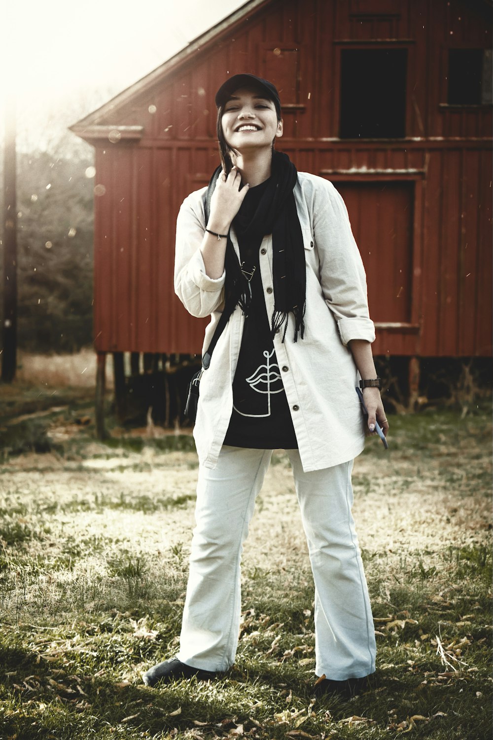 a woman standing in front of a red barn talking on a cell phone