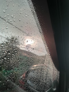 Gentle raindrops falling on a windowpane, blurring the view outside with a peaceful glow.