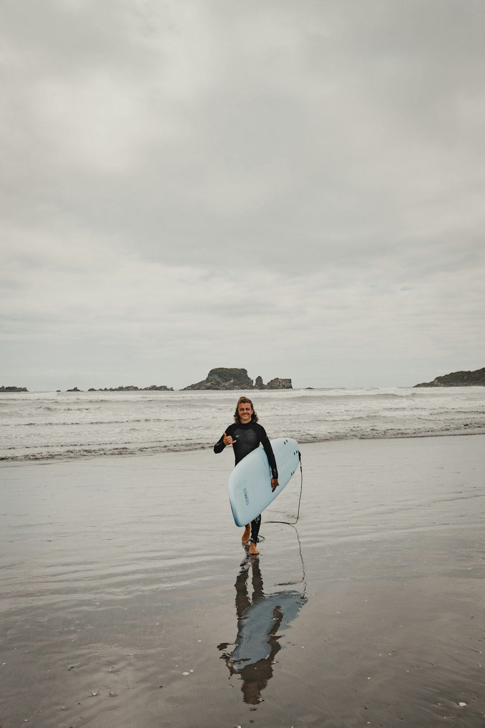 a woman holding a surfboard on top of a beach