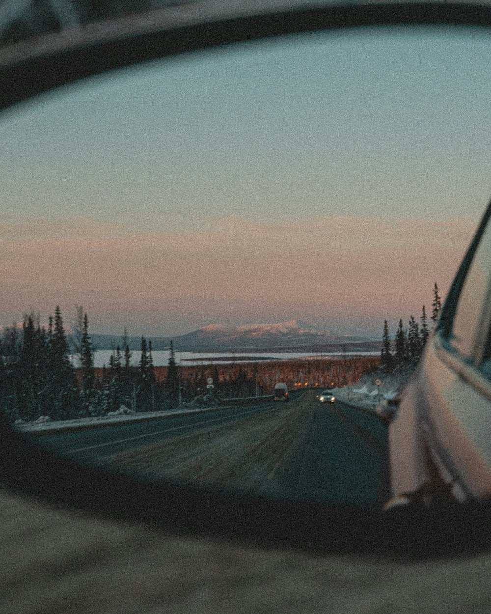 a car's side view mirror reflecting the sunset