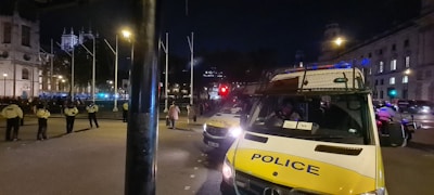 Law enforcement vehicles moving along a city street at dusk.
