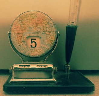 a clock sitting on top of a table next to a pen
