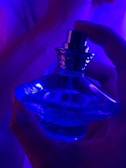 A hand holding a luxurious perfume bottle against a soft background.
