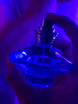 Close-up of hands exchanging a luxurious perfume bottle with a warm, inviting background.
