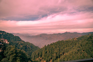 a scenic view of a valley and mountains under a cloudy sky