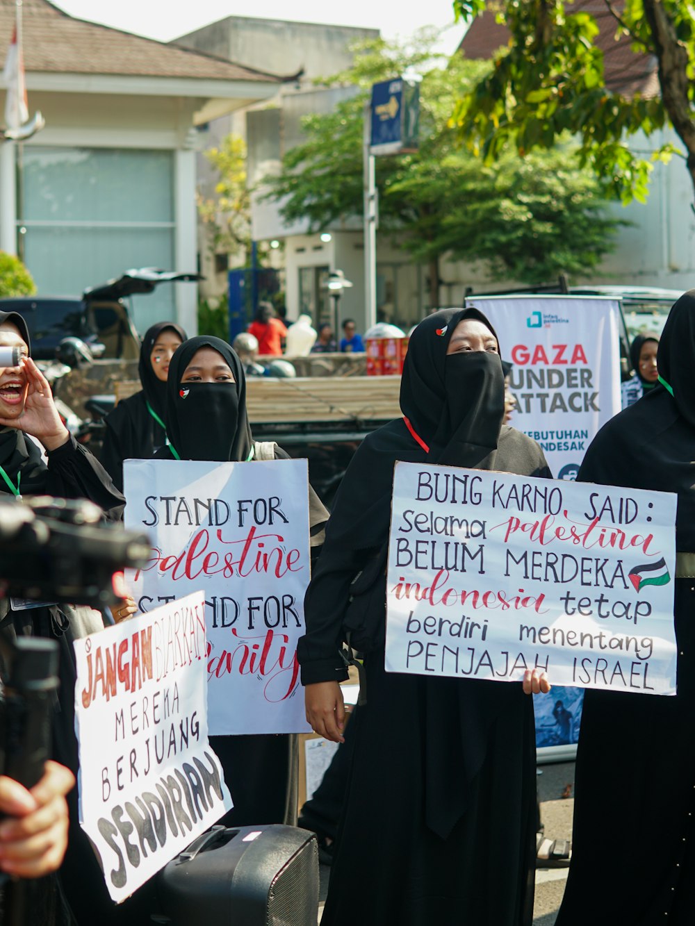 한 무리의 여성들이 건물 앞에서 팻말을 들고 있다