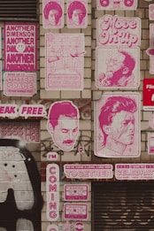 A series of colorful posters and murals are displayed on a brick wall. The art is primarily in pink tones, featuring various musicians and slogans like 'Move On Up,' 'Music Sounds Better With You,' and 'Another Dimension.' There are also images of cassette tapes and stylized portraits of famous musicians.