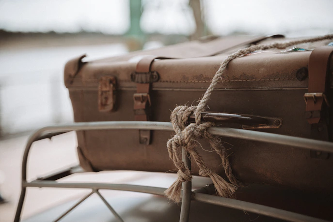 small brown suitcase tied to a rack