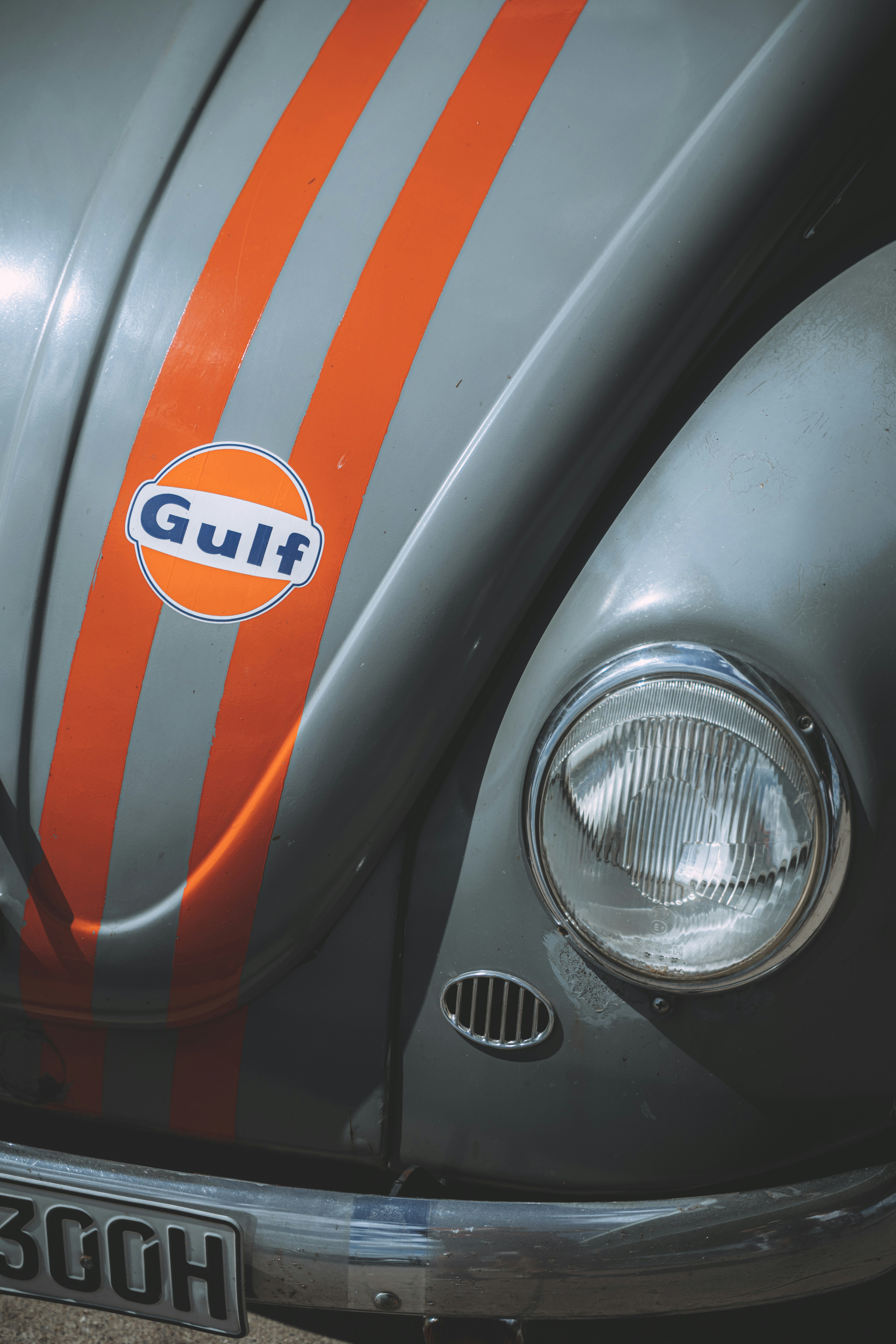 Un primo piano della parte anteriore di un insetto VW grigio e arancione