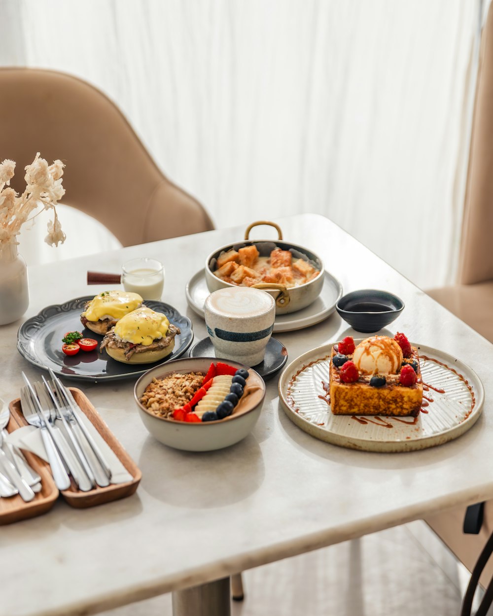 a table topped with plates of food next to a vase of flowers