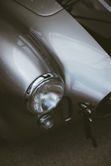 A close-up of a vintage classic car's gleaming chrome details under soft lighting.