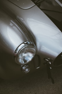 A close-up of a vintage classic car's gleaming chrome details under soft lighting.