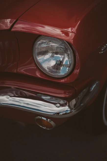 Close-up of the iconic round headlights and chrome bumper of a bright red Beetle