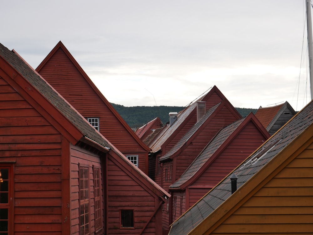 a row of red wooden houses with mountains in the background