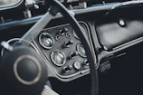 Close-up of a dashboard glowing with retro dials and vibrant neon lights inside a classic car.