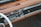 A vintage car dashboard featuring a classic radio with tuning dials and buttons. The dashboard is made of brown leather and wood, with a smooth and polished finish. The design includes chrome accents and an analog clock.