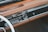 A vintage car dashboard featuring a classic radio with tuning dials and buttons. The dashboard is made of brown leather and wood, with a smooth and polished finish. The design includes chrome accents and an analog clock.