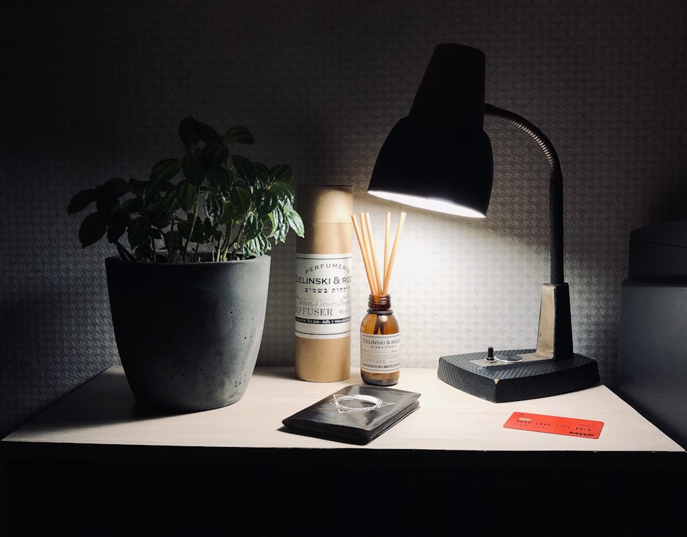 a desk with a lamp, a plant and a cell phone