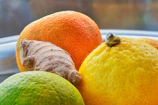 Close-up of CitrusBurn supplement bottle surrounded by fresh citrus fruits and green tea leaves.