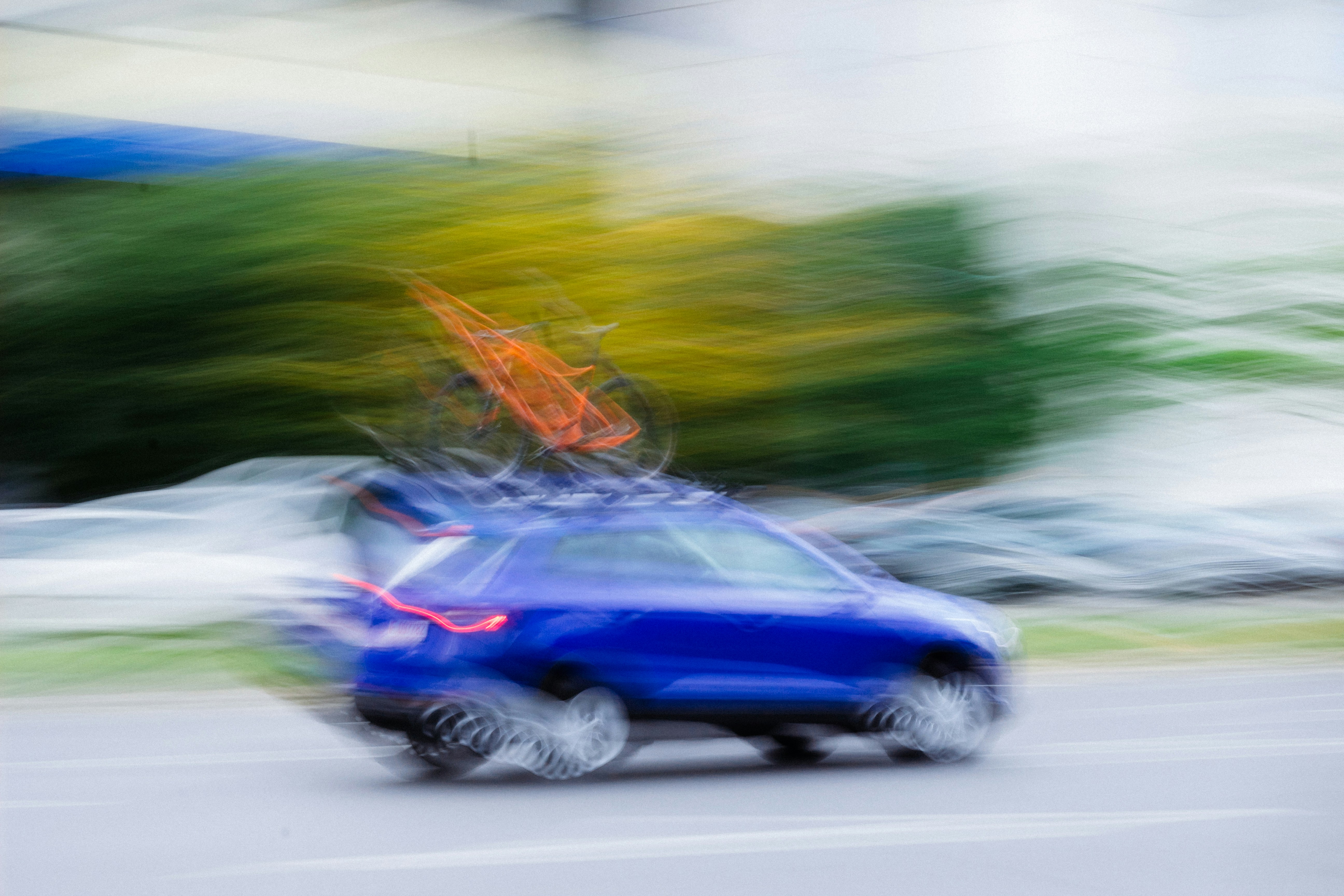 a blurry photo of a blue car driving down a street