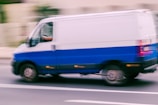 a blue and white van driving down a street