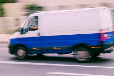 a blue and white van driving down a street